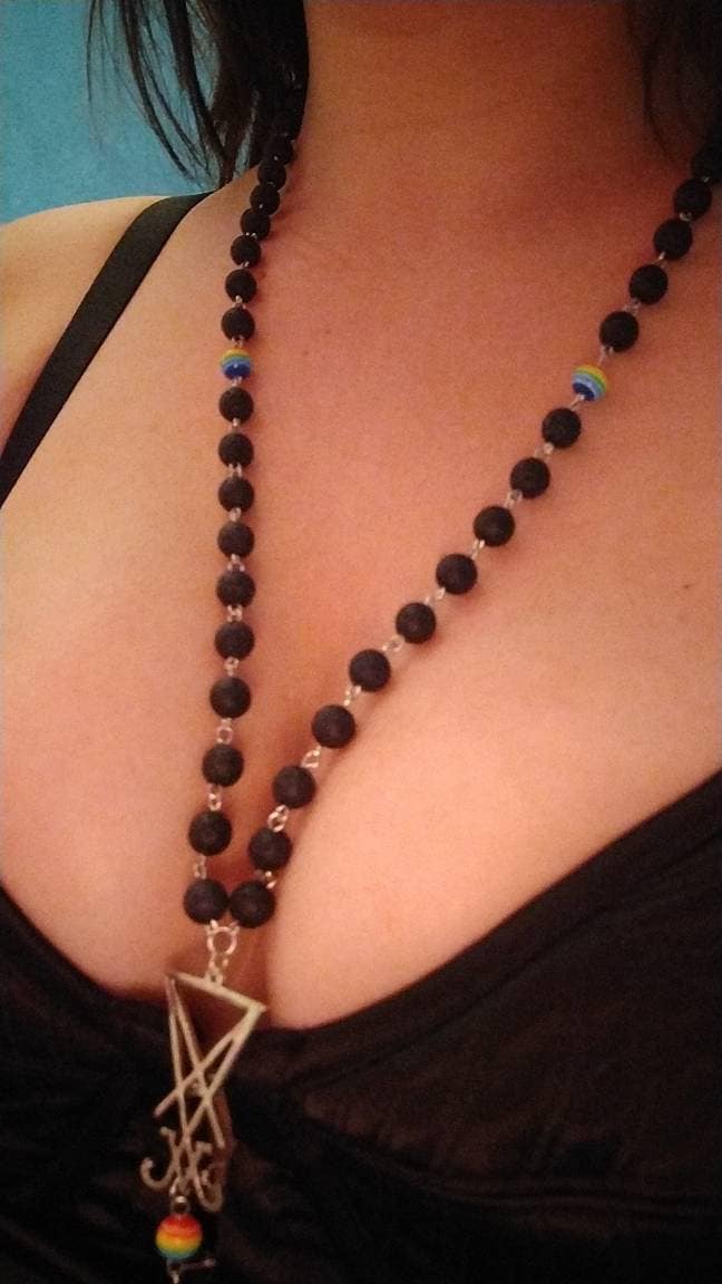 rosary sits nicely between the bosom, textured lava beads, signil of satanic temple and rainbow beads